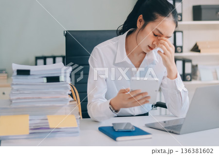Asian business woman experiences work stress headache in modern office reviewing financial report data analysis overwhelmed professional employee burnout difficult project 136381602