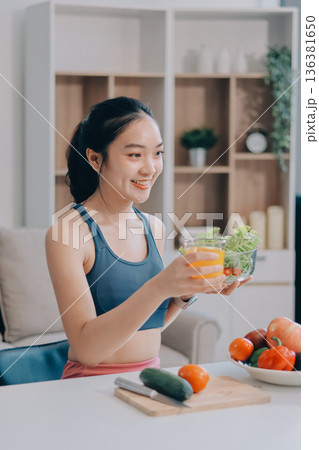 Fit young Asian women in activewear sitting on yoga mat and eating fresh vegetable salad after workout, representing clean eating, fitness lifestyle, wellness routine and health balance. Fit young Asian women in activewear sitting on yoga mat and eating fresh vegetable salad after workout, representing clean eating, fitness lifestyle, wellness routine and health balance. 136381650