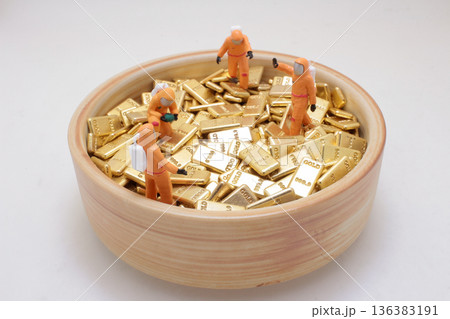 Miniature hazmat workers inspect bowl filled with gold Miniature hazmat workers inspect bowl filled with gold 136383191