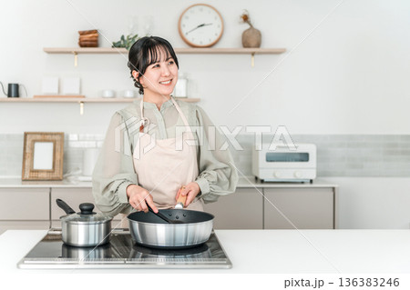 キッチンで料理をするエプロン姿の若いアジア人女性 136383246