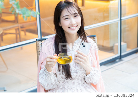 カフェのテラス席でスマホを見る女性 カフェのテラス席でスマホを見る女性 136383324