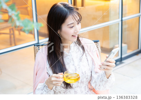カフェのテラス席でスマホを見る女性 カフェのテラス席でスマホを見る女性 136383328