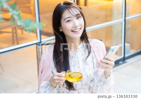 カフェのテラス席でスマホを見る女性 カフェのテラス席でスマホを見る女性 136383330