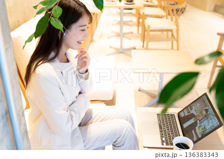 カフェのソファー席に座りパソコンでリモート会議をしている若い女性 カフェのソファー席に座りパソコンでリモート会議をしている若い女性 136383343