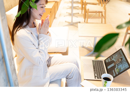カフェのソファー席に座りパソコンでリモート会議をしている若い女性 136383345