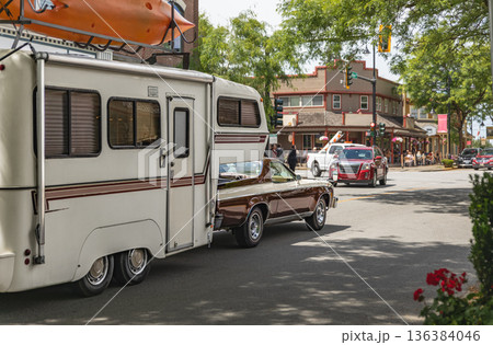 Classic car with A Camper Trailer driving through the city. 136384046