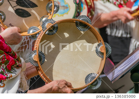 Experienced hands of Galician cantareiras passionately playing a traditional tambourine in a festive and colorful atmosphere. Experienced hands of Galician cantareiras passionately playing a traditional tambourine in a festive and colorful atmosphere. 136385000