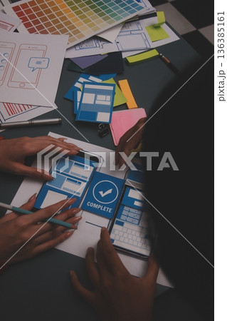 Team of uxui designers pointing at computer screen, discussing new mobile app design in the office 136385161