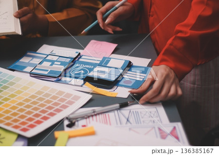 Team of uxui designers pointing at computer screen, discussing new mobile app design in the office 136385167