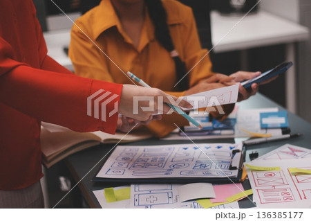 Team of uxui designers pointing at computer screen, discussing new mobile app design in the office 136385177