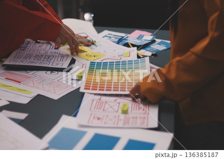 Team of uxui designers pointing at computer screen, discussing new mobile app design in the office 136385187