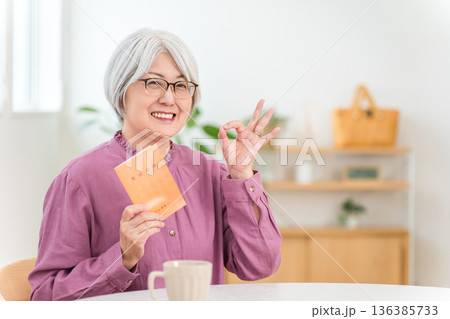 年金手帳を持つグレイヘアのシニア女性 136385733