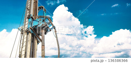 Heavy drilling rig stands tall against a backdrop of clouds while working to extract oil and gas resources during daytime at a drilling site 136386366
