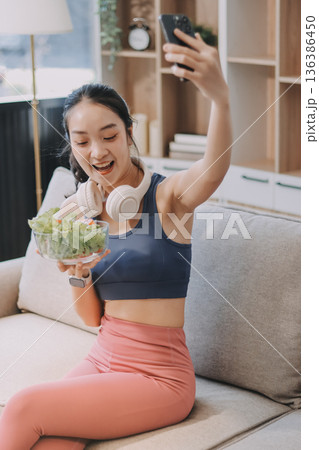 Fit young Asian women in activewear sitting on yoga mat and eating fresh vegetable salad after workout, representing clean eating, fitness lifestyle, wellness routine and health balance. Fit young Asian women in activewear sitting on yoga mat and eating fresh vegetable salad after workout, representing clean eating, fitness lifestyle, wellness routine and health balance. 136386450