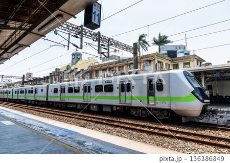 A local train (EMU900 series) is stopped on the platform of the Hsinchu Railway Station. It was the oldest station in Taiwan, now listed as a national monument. 136386849