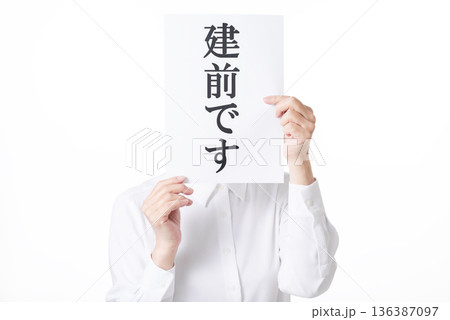 建前ですと書かれた紙を両手で持つ白いシャツを着た人物 136387097