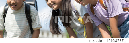 のぞき込む青空と学校背景の笑顔の小学生(子供）　ワクワクする楽しいイメージ	顔無し 136387274