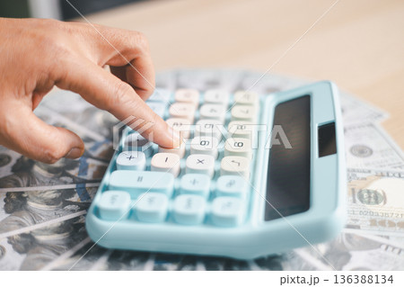 Close-up of a hand pressing calculator keys for budgeting, accounting and financial analysis. Business expense planning, tax calculation, office desk background, copy space for paperwork. 136388134