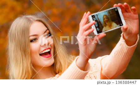 girl taking self picture with phone outdoors 136388447