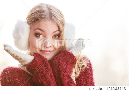 Portrait of pretty smiling woman in white earmuffs. 136388448