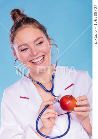 Dietitian examine apple fruit with stethoscope. Dietitian examine apple fruit with stethoscope. 136388707