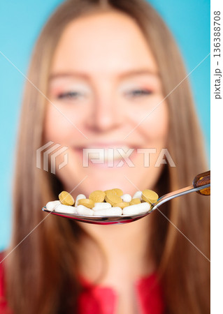 Young woman eating pills on a spoon 136388708
