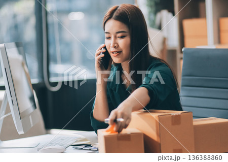 Starting small businesses SME owners female entrepreneurs check online orders to prepare to pack the boxes, sell to customers, sme business ideas online. Starting small businesses SME owners female entrepreneurs check online orders to prepare to pack the boxes, sell to customers, sme business ideas online. 136388860