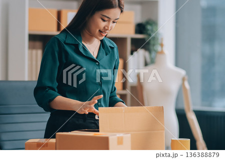 Starting small businesses SME owners female entrepreneurs check online orders to prepare to pack the boxes, sell to customers, sme business ideas online. Starting small businesses SME owners female entrepreneurs check online orders to prepare to pack the boxes, sell to customers, sme business ideas online. 136388879