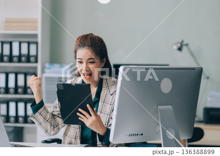 Determined asian businesswoman works late in a modern office, confidently analyzing data on her laptop, embodying success and professionalism with a smile Determined asian businesswoman works late in a modern office, confidently analyzing data on her laptop, embodying success and professionalism with a smile 136388899