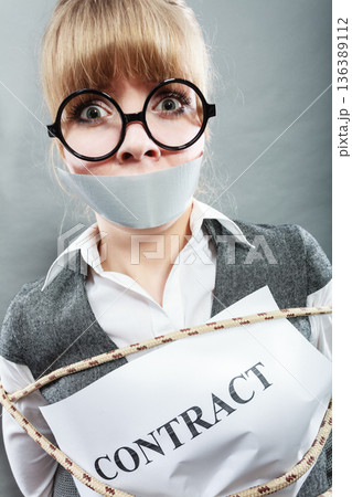 Businesswoman bound by contract with taped mouth. Businesswoman bound by contract with taped mouth. 136389112