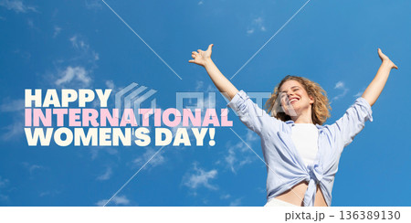 A woman joyfully celebrates Women's Day under a bright sky A woman joyfully celebrates Women's Day under a bright sky 136389130
