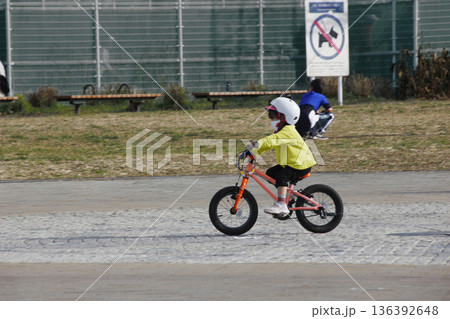 自転車の練習をするカワイイ女の子の赤い自転車と白いヘルメット 136392648