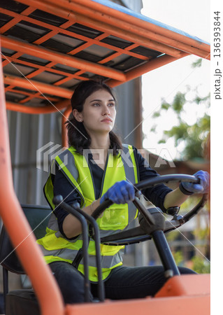 Woman worker at forklift driver happy working in industry factory logistic ship.  136393844