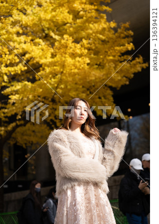 秋の公園で銀杏並木を散策する女性 136394121