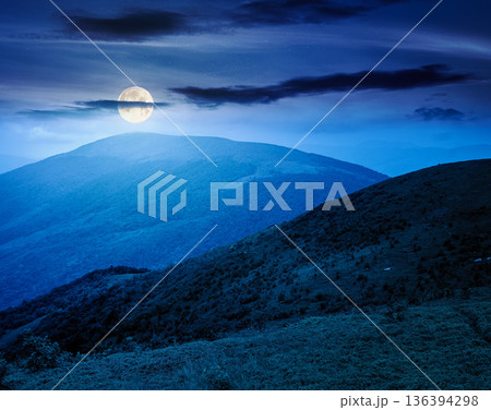 wonderful summer landscape in mountains at night. scenic alpine view of rolling hills and meadow in full moon light. cloudy sky. finance investment or abstract concepts 136394298