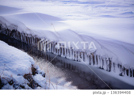 雪の積もった田んぼと用水路:冬の農業用水と雪原の風景 雪の積もった田んぼと用水路:冬の農業用水と雪原の風景 136394408