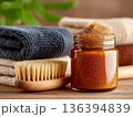 Natural body scrub jar with brush and towels arranged in a spa wellness concept. Organic skincare and clean beauty lifestyle. Perfect for cosmetic branding, spa marketing and wellness concepts. 136394839