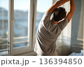 Faceless young man doing morning stretch with stretching the back by window. Wellness morning routine. Flexibility, relaxation, mindfulness, active healthy lifestyle, daily movement, morning body care 136394850