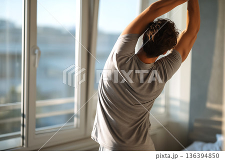 Faceless young man doing morning stretch with stretching the back by window. Wellness morning routine. Flexibility, relaxation, mindfulness, active healthy lifestyle, daily movement, morning body care Faceless young man doing morning stretch with stretching the back by window. Wellness morning routine. Flexibility, relaxation, mindfulness, active healthy lifestyle, daily movement, morning body care 136394850