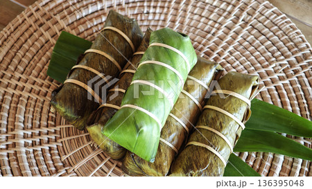 Sticky rice stir-fried with coconut milk, wrapped in banana leaves, with a banana filling. 136395048