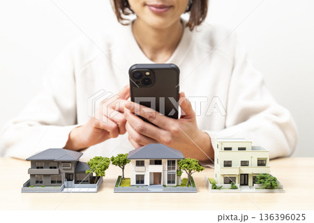 住宅模型を比較する女性 136396025