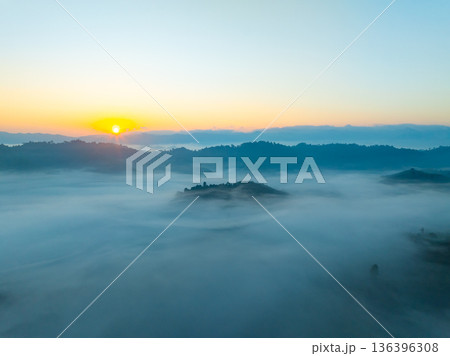 Aerial view of flowing fog waves on mountain tropical rainforest,Bird eye view image over the clouds Amazing nature background with clouds and mountain peaks in Thailand 136396308