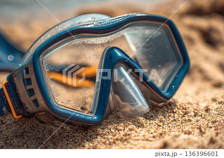 A close-up of snorkeling gear: a mask and snorkel resting on warm, dry sand, ready for the next underwater adventure. A close-up of snorkeling gear: a mask and snorkel resting on warm, dry sand, ready for the next underwater adventure. 136396601