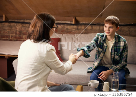 Teenage boy shaking hands with psychologist after successful therapy session. 136396754
