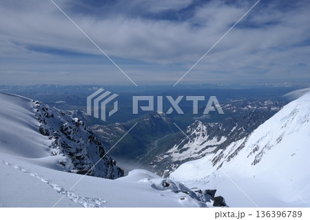 A stunning rock formation covered in snow, set against a clear blue sky with fluffy clouds in the background, creating a peaceful and breathtaking mountain landscape. A stunning rock formation covered in snow, set against a clear blue sky with fluffy clouds in the background, creating a peaceful and breathtaking mountain landscape. 136396789