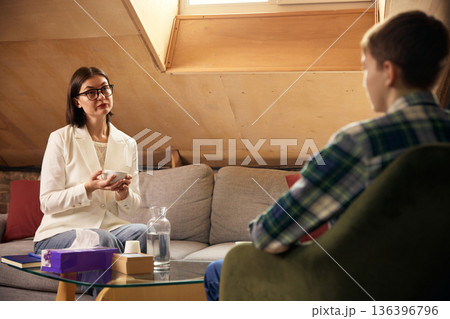 Teenage boy talking with female psychologist during therapy session. Teenage boy talking with female psychologist during therapy session. 136396796