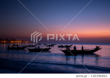 The serene scene of Comorian artisanal fishing boats returning to shore at dusk, their lights twinkling on the horizon. 136396862