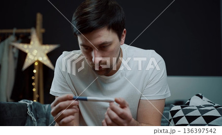 A portrait of a man in deep despair clutching a pregnancy test. The image captures a moment of intense emotional breakdown and mental exhaustion regarding family news A portrait of a man in deep despair clutching a pregnancy test. The image captures a moment of intense emotional breakdown and mental exhaustion regarding family news 136397542