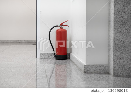 Red fire extinguisher securely positioned in a bright, modern building corridor, symbolizing crucial safety, emergency readiness, and fire protection measures 136398018