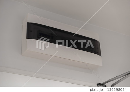 Sleek electrical fuse box with a dark translucent cover on a white wall, highlighting essential home safety and modern power distribution infrastructure 136398034